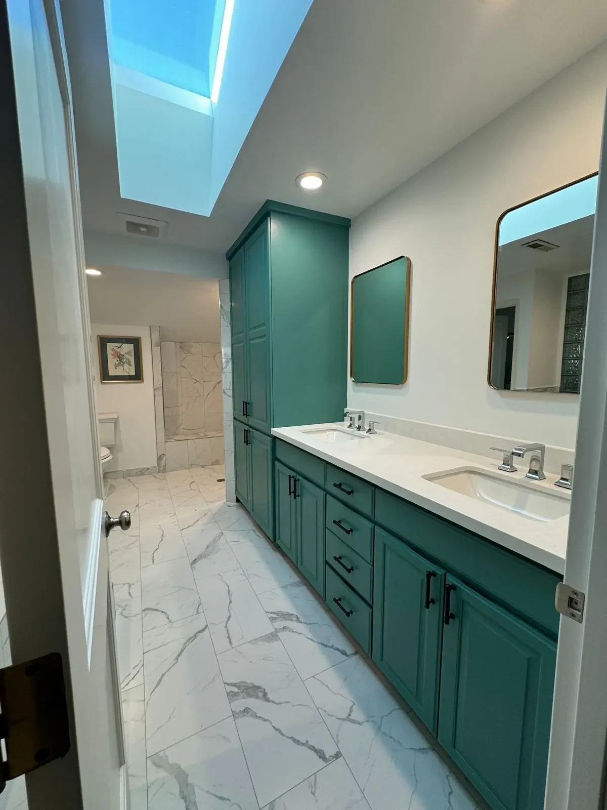 Teal bathroom cabinetry, white vanity and skylight