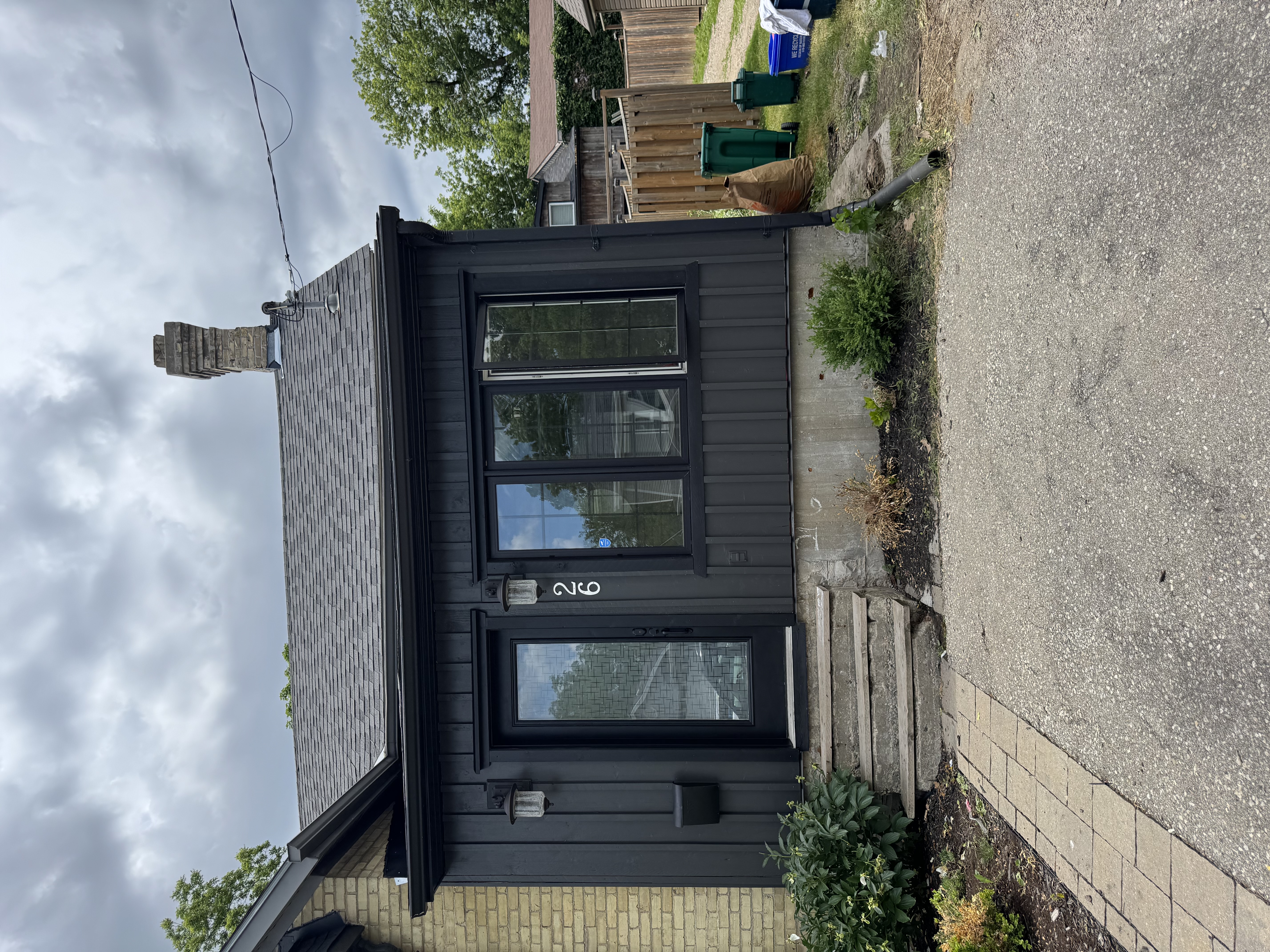 Yellow brick home with black painted trim and siding by Premier Pro Painting in Kitchener