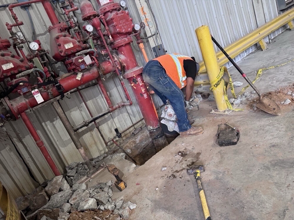 Crew member digging out a fire line riser inside a commercial facility