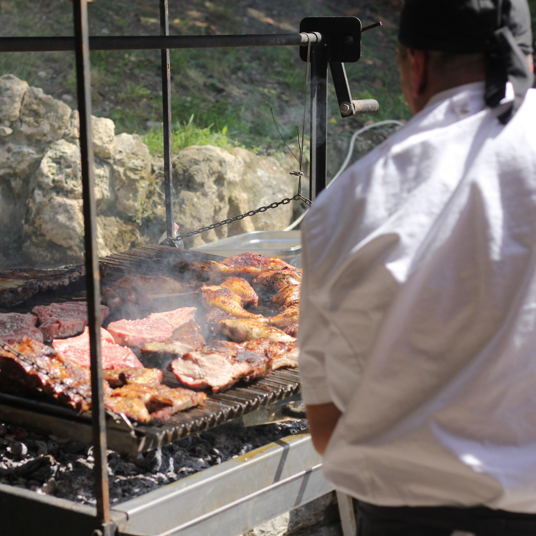 Asador al lavoro davanti alla griglia accesa