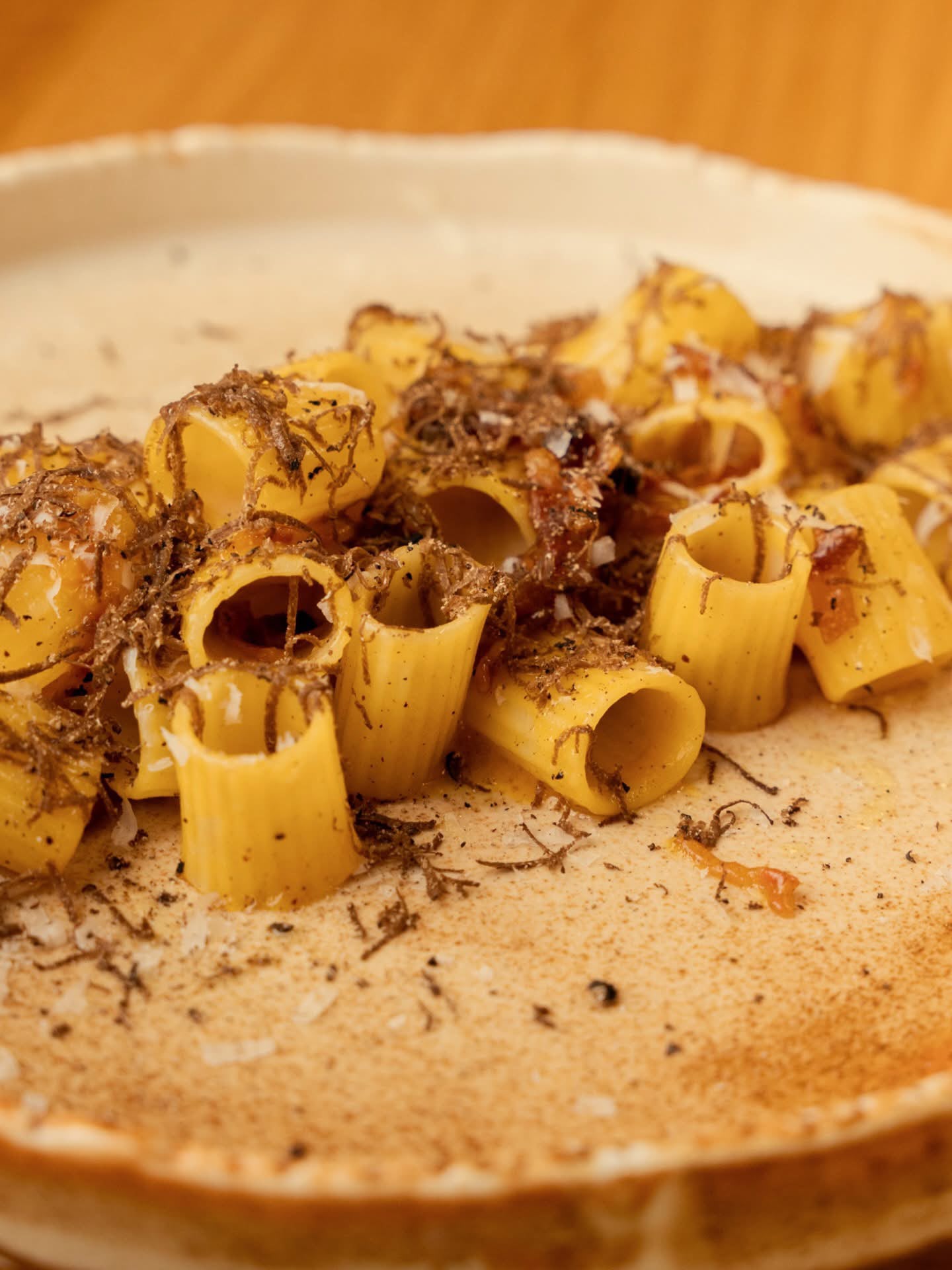 Pasta corta con scaglie di tartufo, servita su un piatto in ceramica