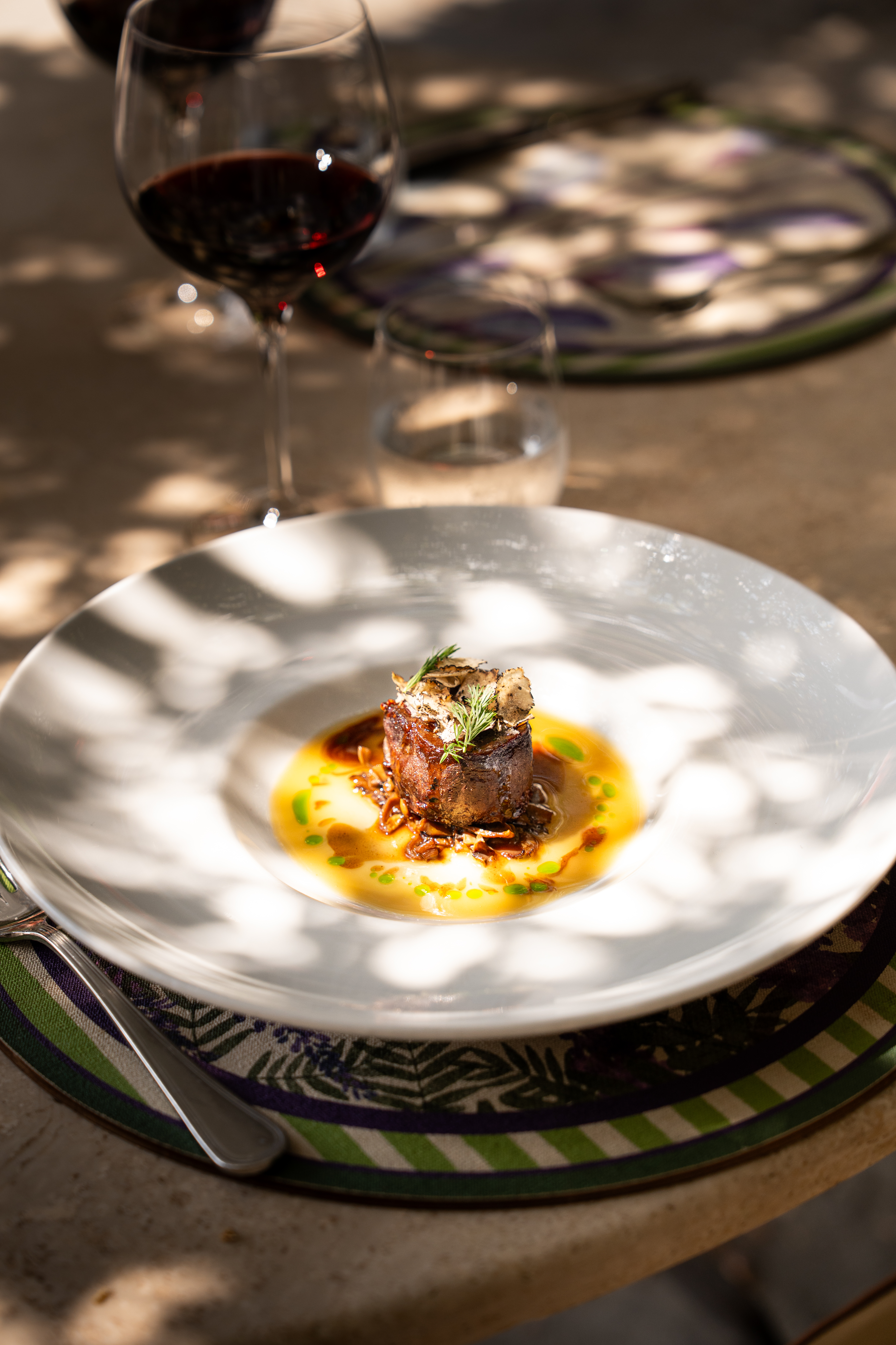 Piatto di carne al tavolo con un calice di vino rosso