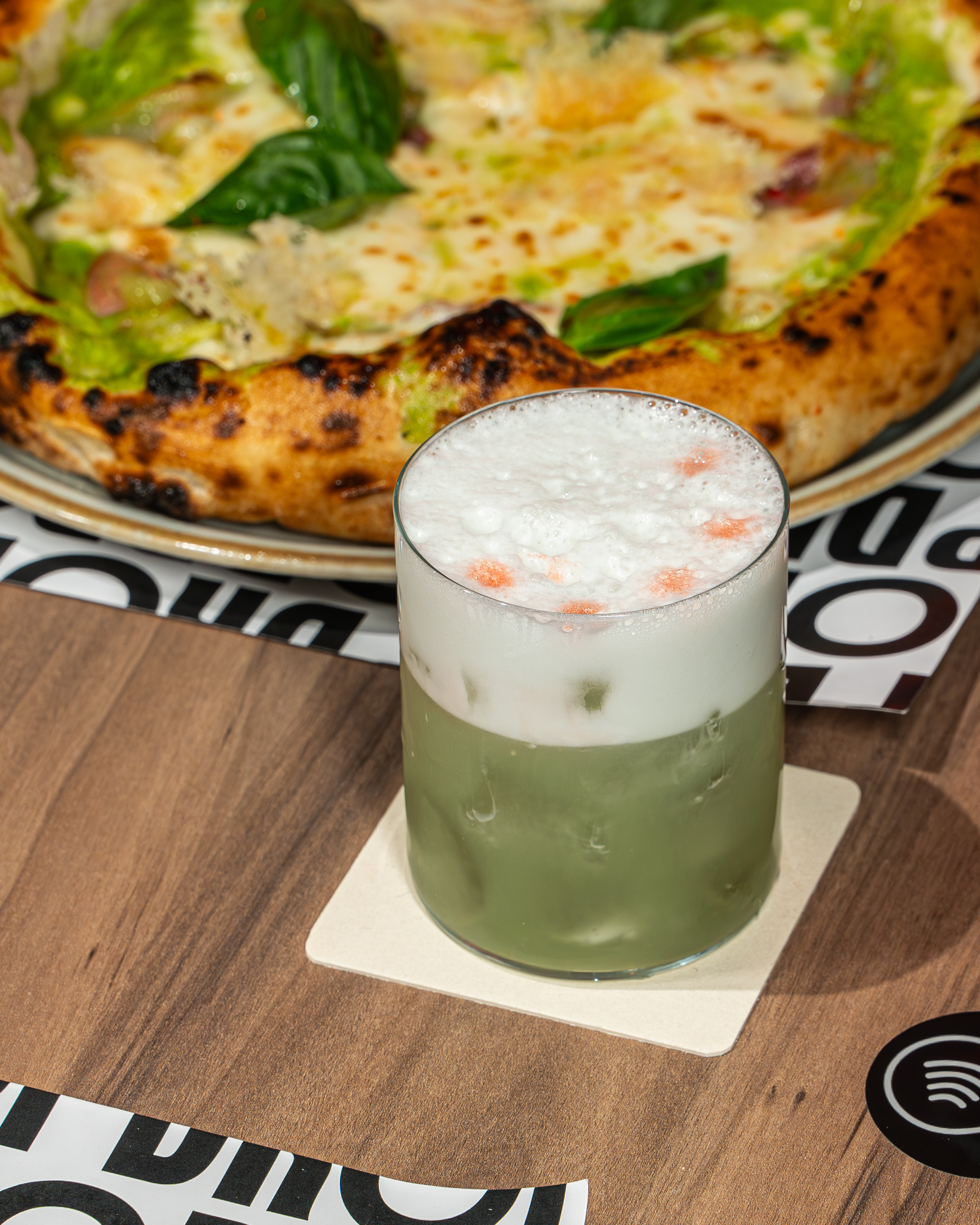 Una pizza contemporanea DROP abbinata a un cocktail verde con una soffice spuma