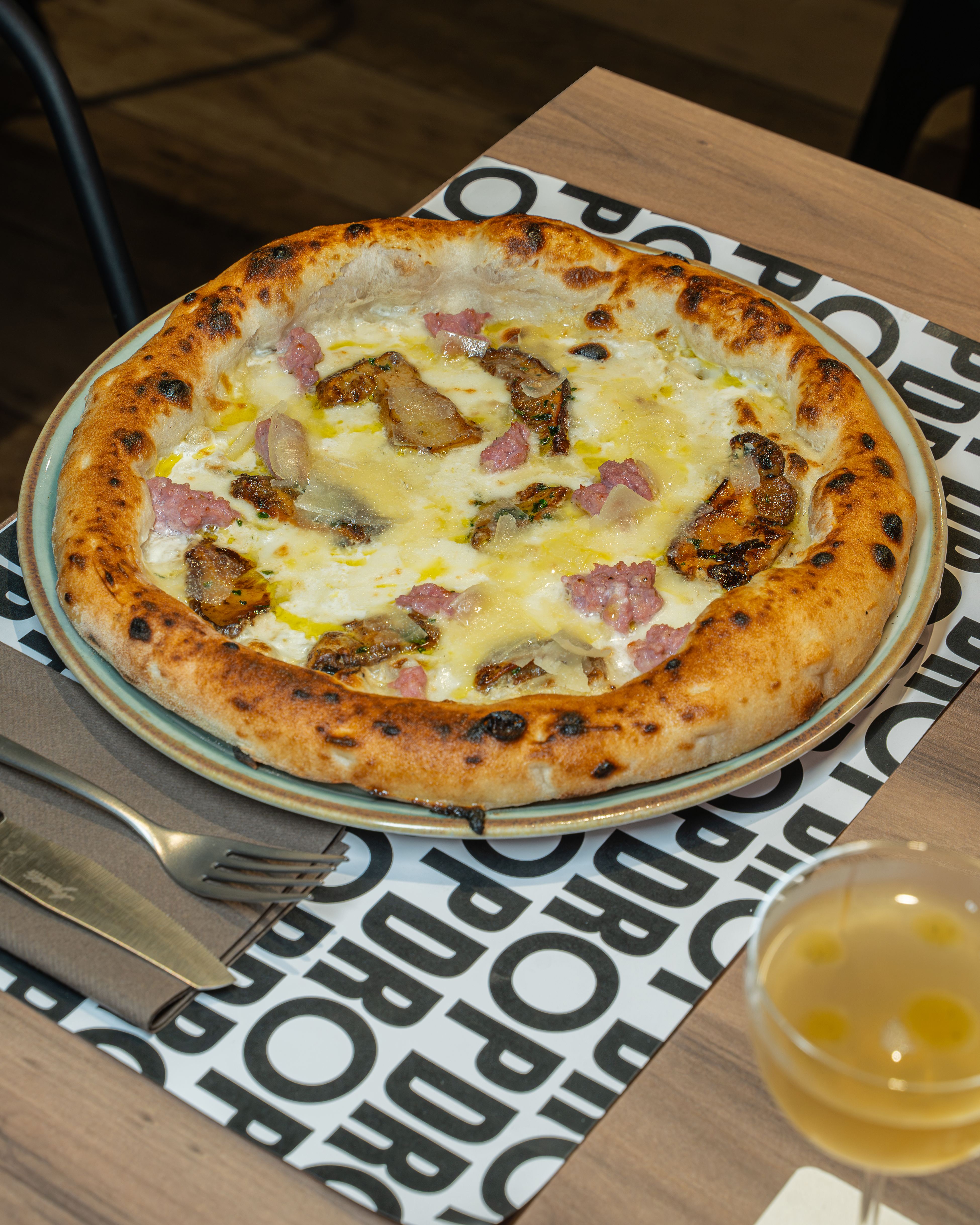 Un’altra pizza della carta DROP, servita al tavolo accanto a un cocktail