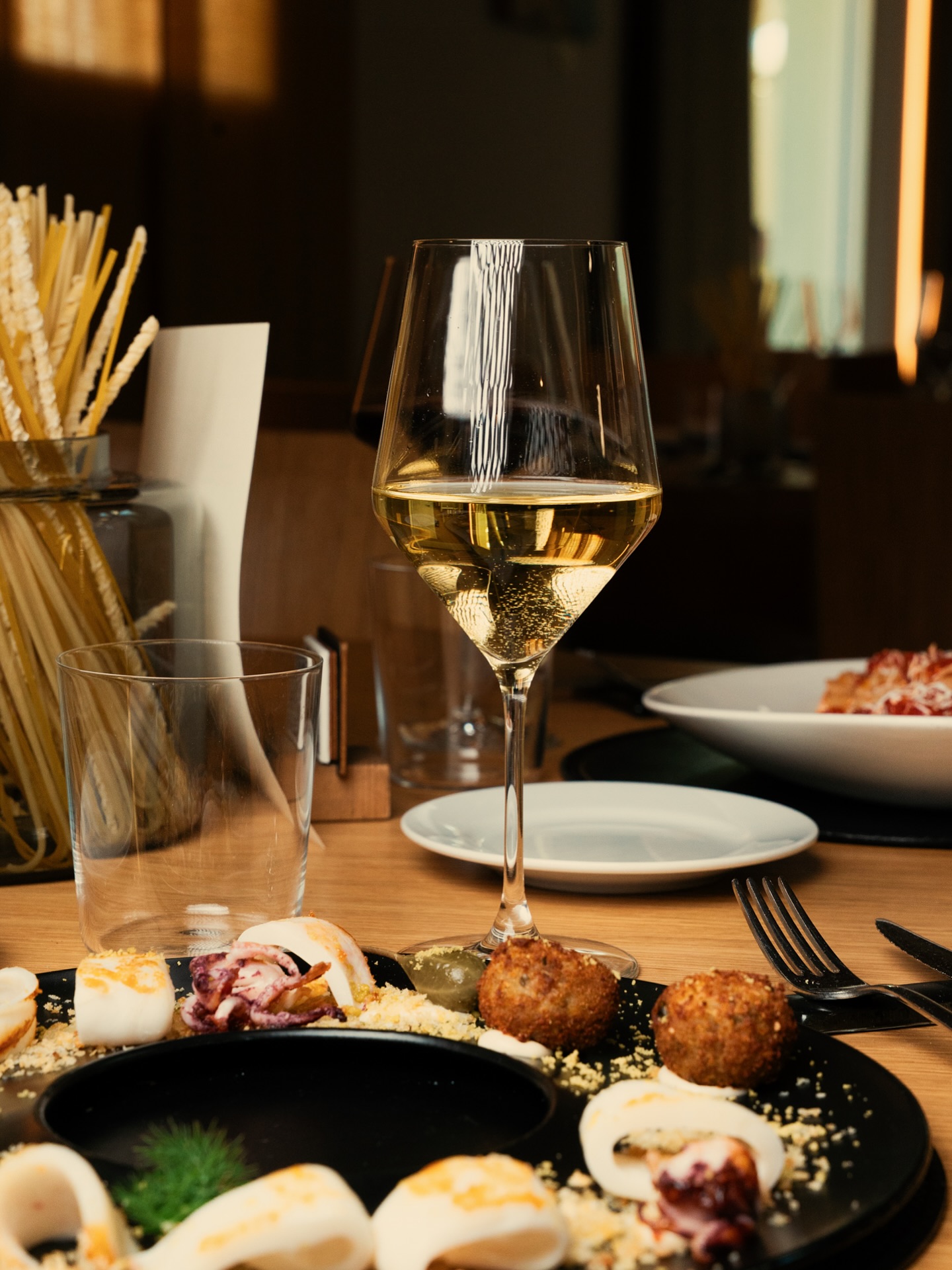 Calice di vino e piatti su una tavola apparecchiata al Ristorante MO