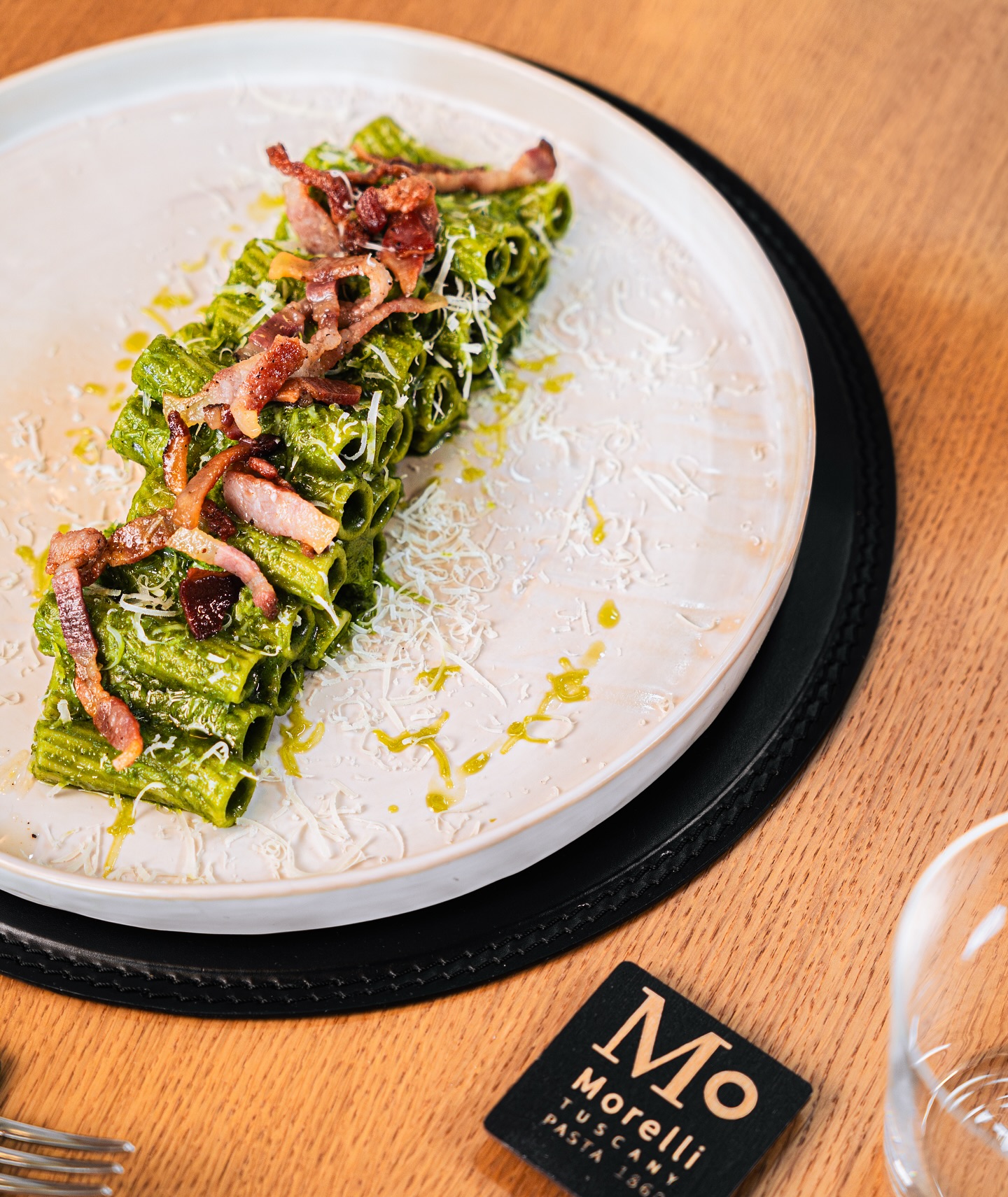 Pasta verde Morelli impiattata, con il marchio MO sul tavolo