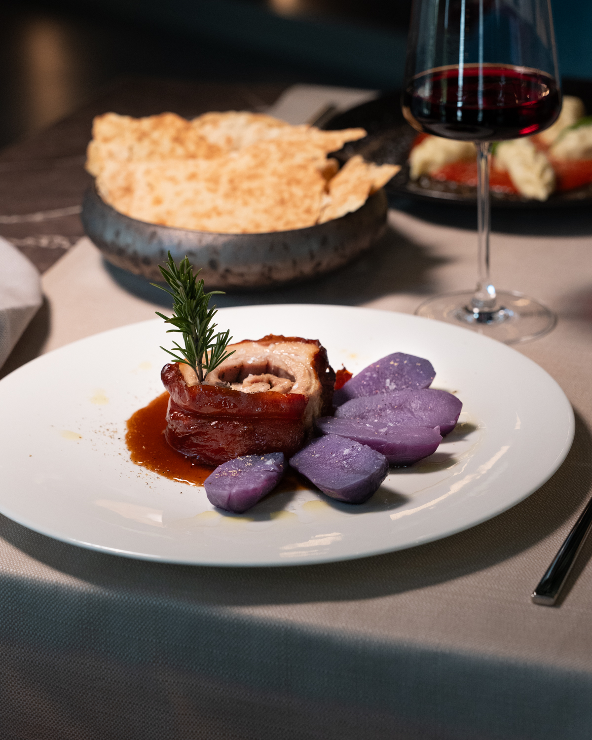 Un piatto di carne con verdure, pane e un calice di vino rosso