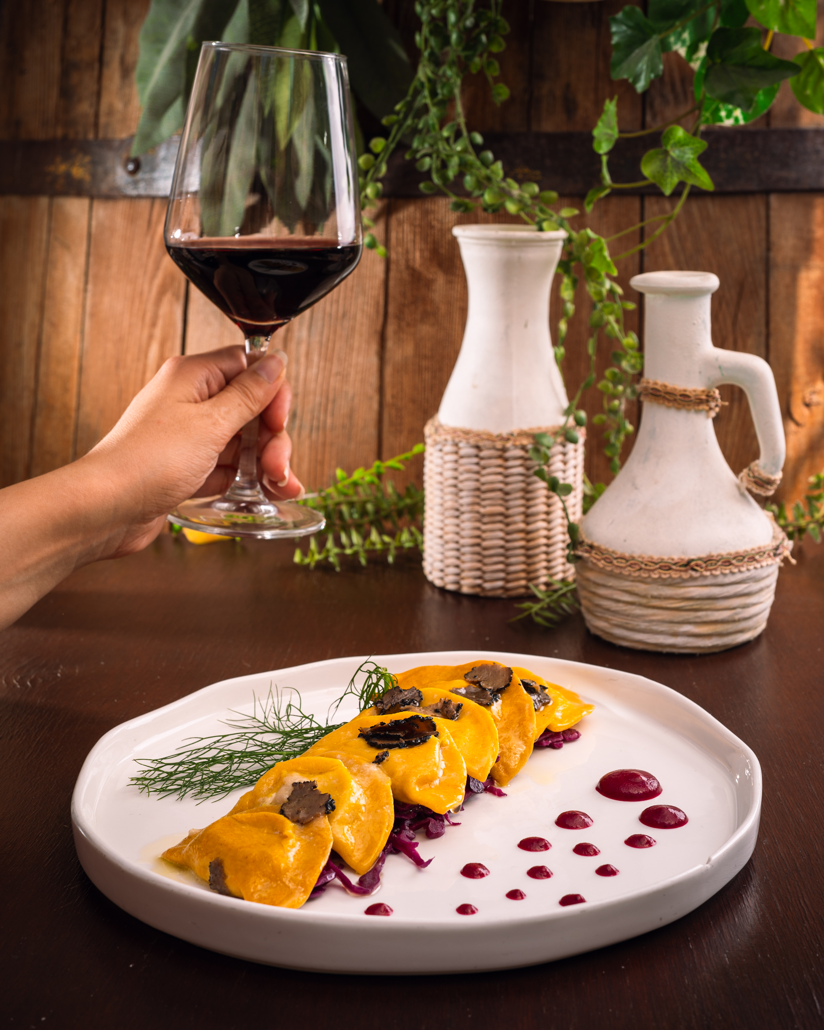 Calice di vino rosso sopra un piatto di ravioli al tartufo