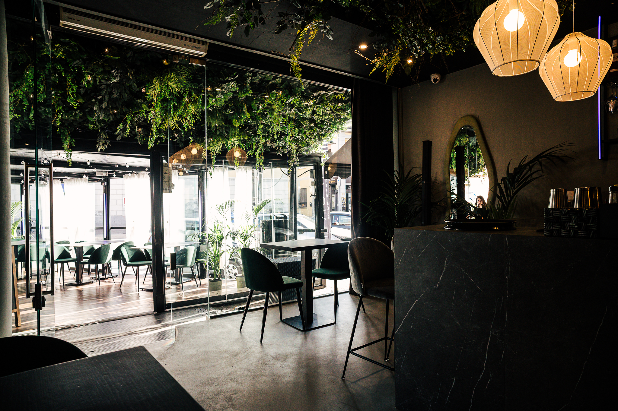 La sala di AURA CLUB GARDEN tra piante, vetrate e lampade sospese