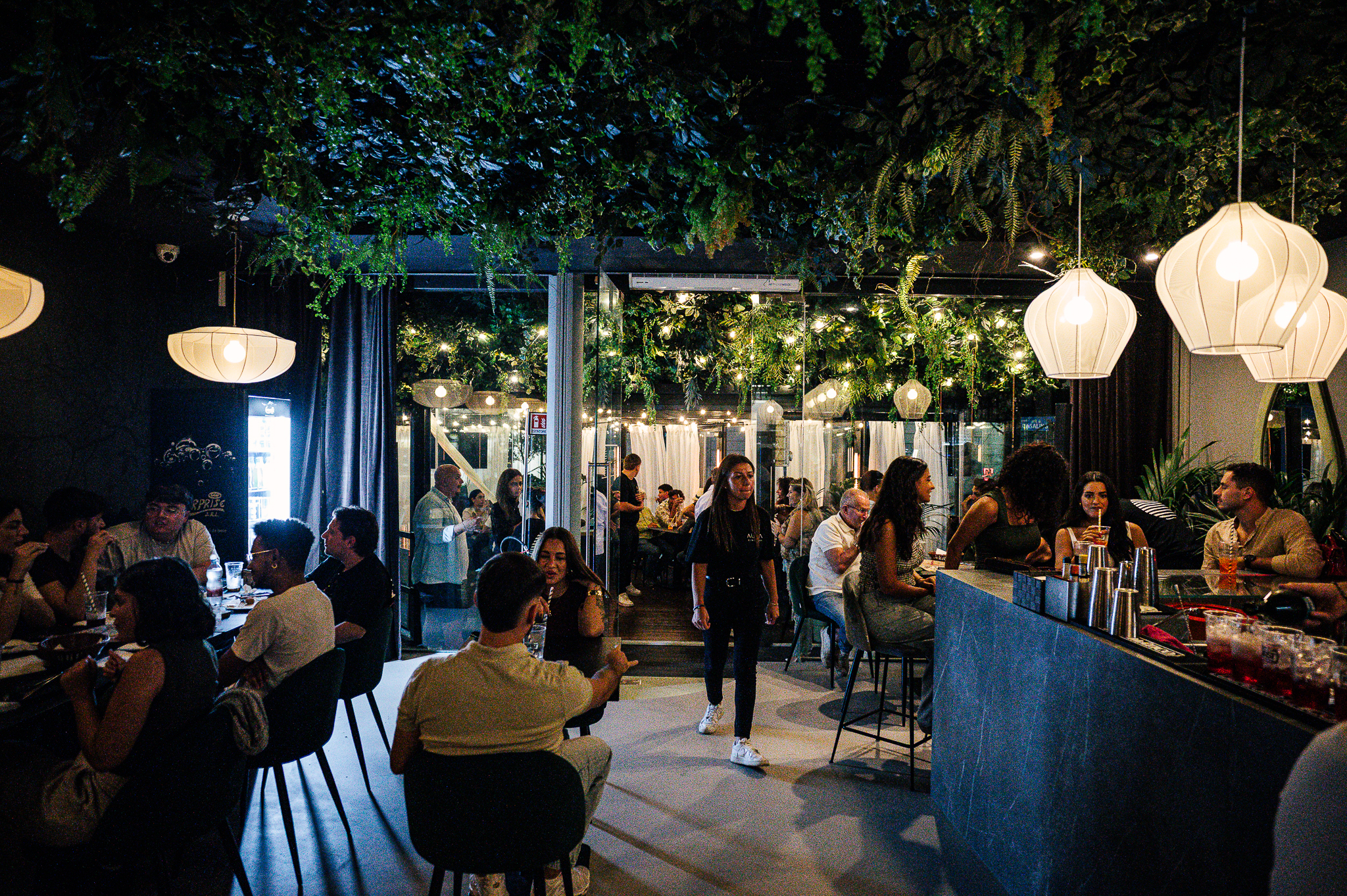 Ospiti a tavola e al bancone nella sala serale di AURA CLUB GARDEN
