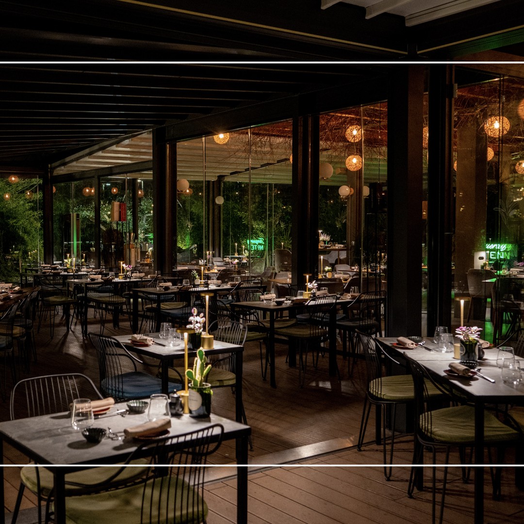La sala veranda di Botanic Fusion con luci soffuse e tavoli apparecchiati