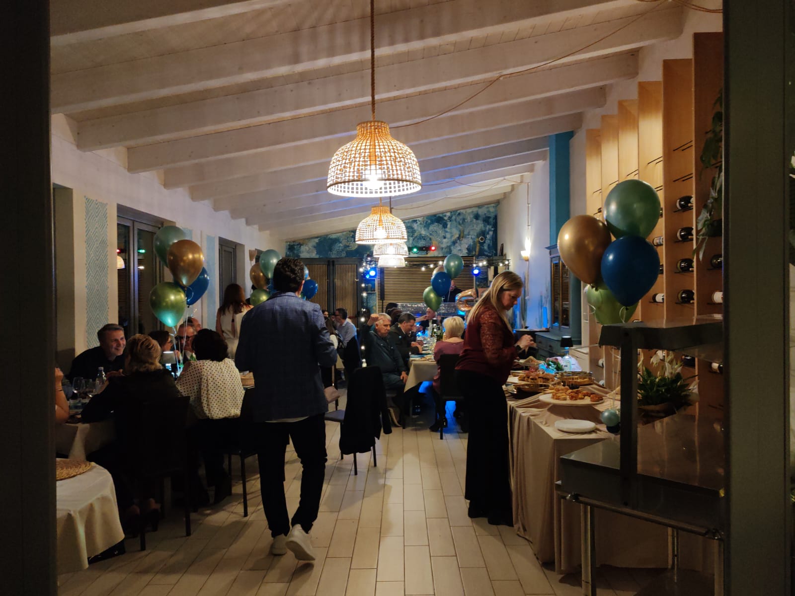 Gli ospiti si ritrovano nella sala di Sibilla, allestita per un evento con tavoli e palloncini