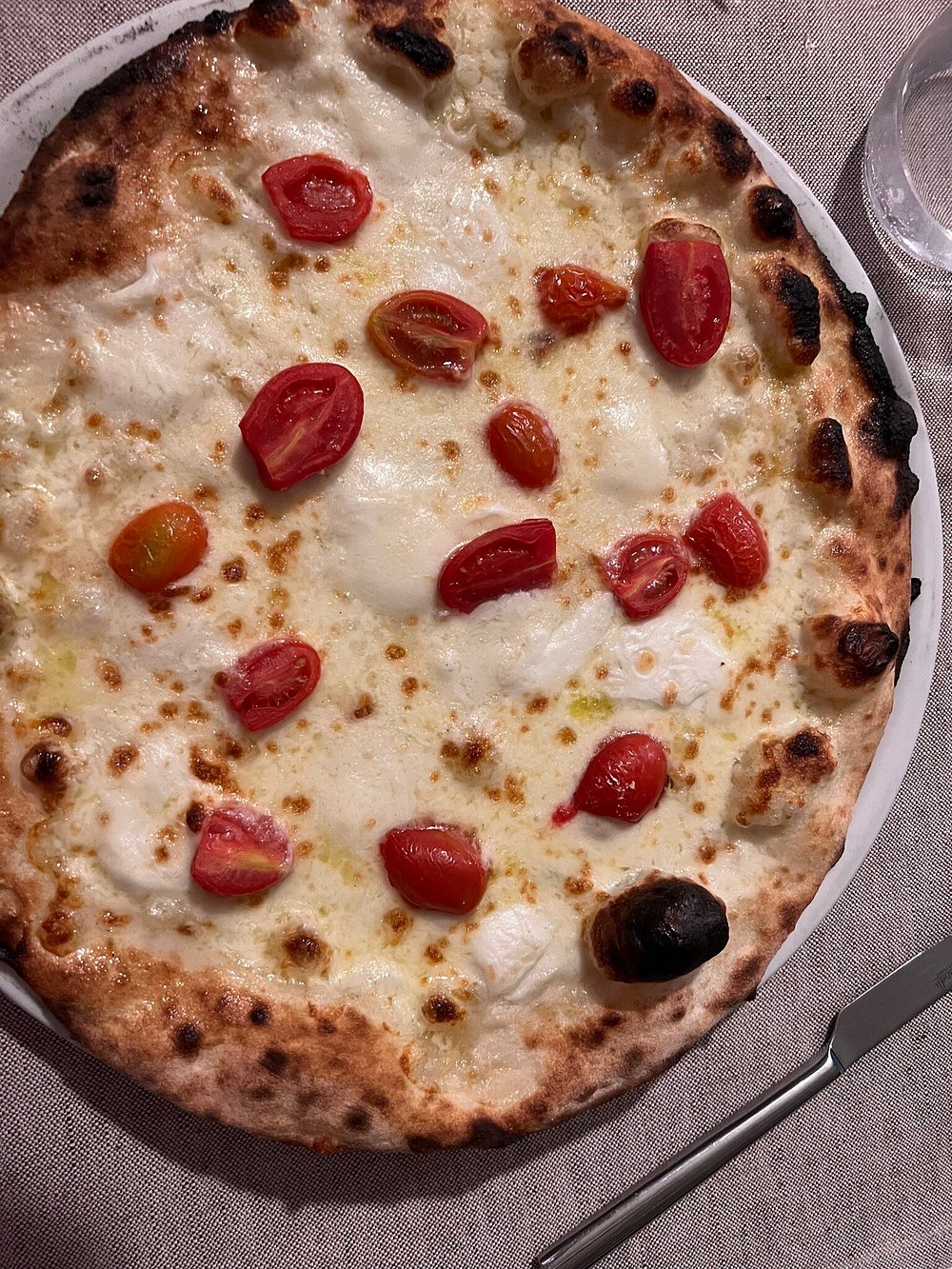 Pizza bianca con mozzarella, stracciatella e pomodorini, appena sfornata