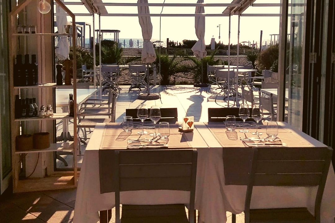 La sala del Levante con i tavoli apparecchiati e la terrazza affacciata sul mare di Fregene