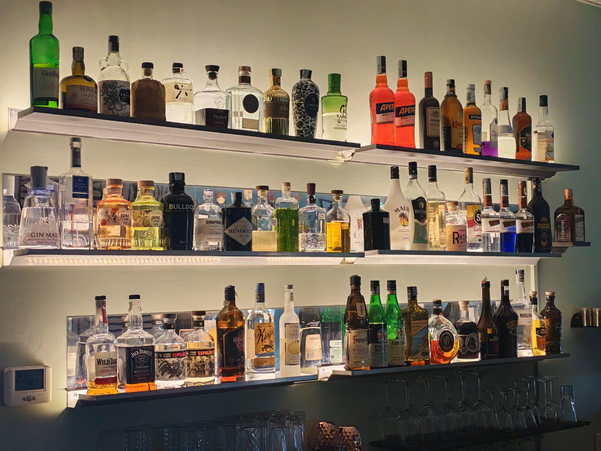 La bottigliera illuminata del bar di Sibilla, con una selezione di gin, whisky e liquori
