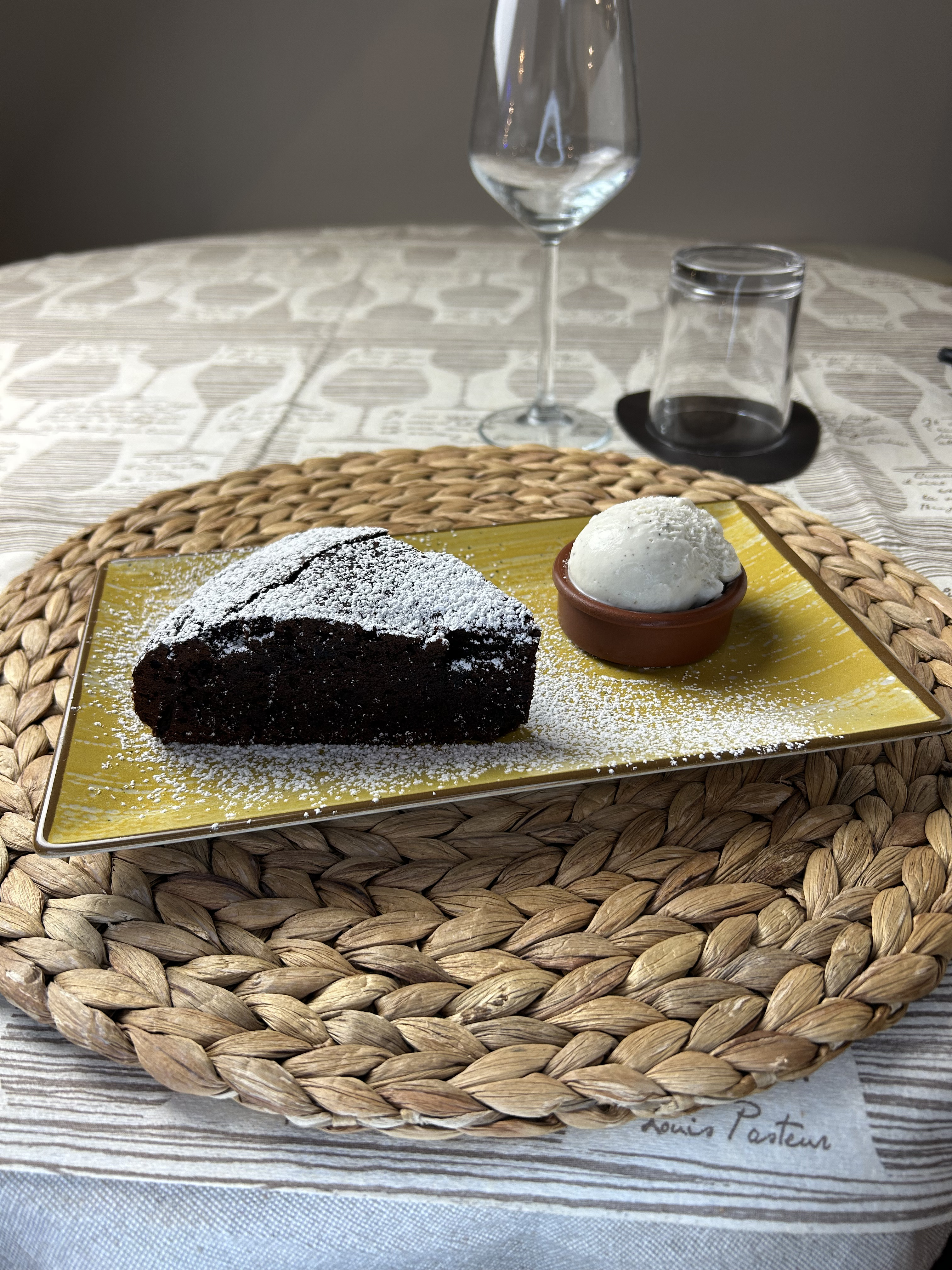 Torta al cioccolato con zucchero a velo e gelato, con un calice a tavola