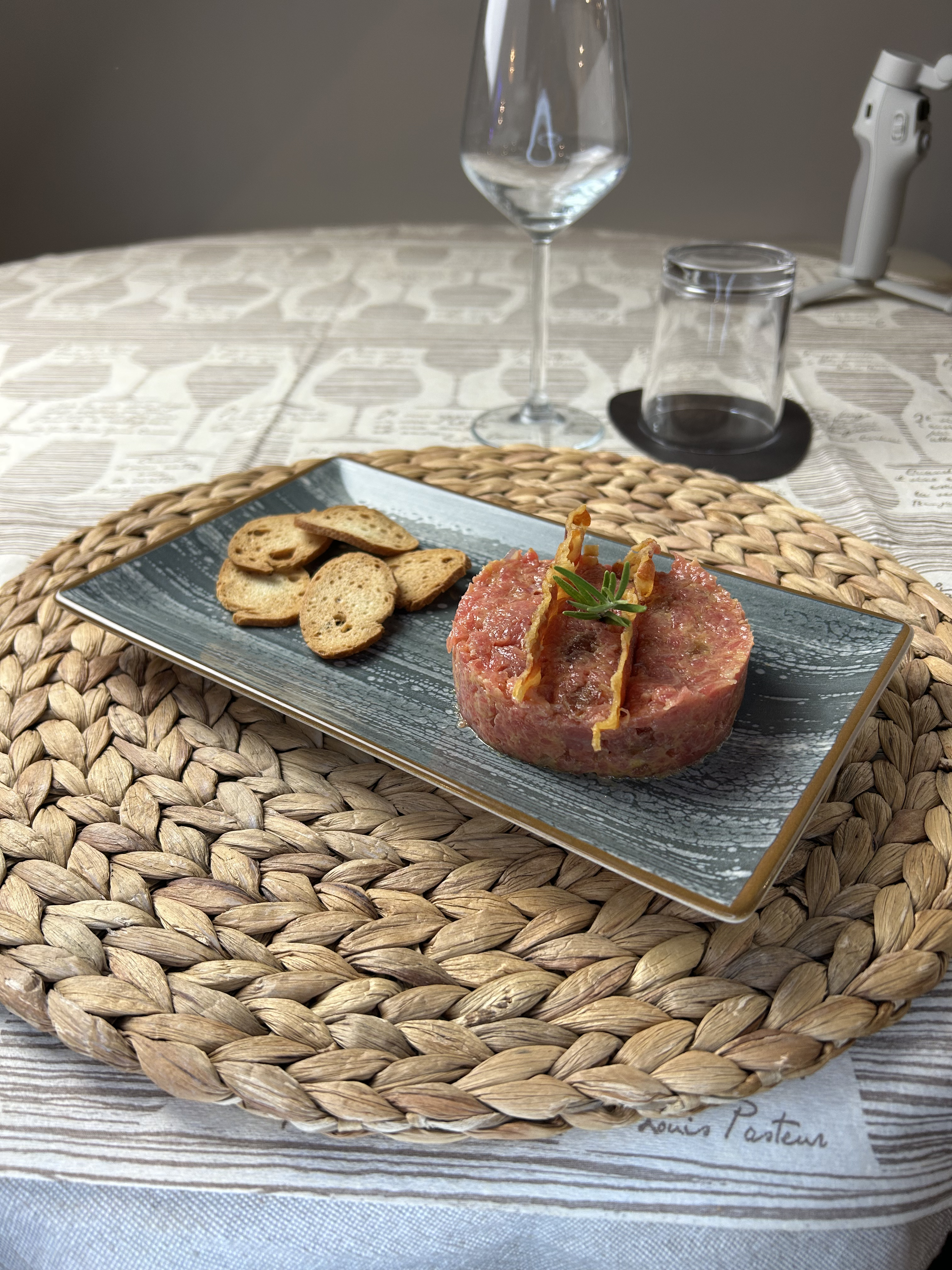 Tartare di Fassona piemontese battuta a coltello, servita con crostini e un calice sullo sfondo