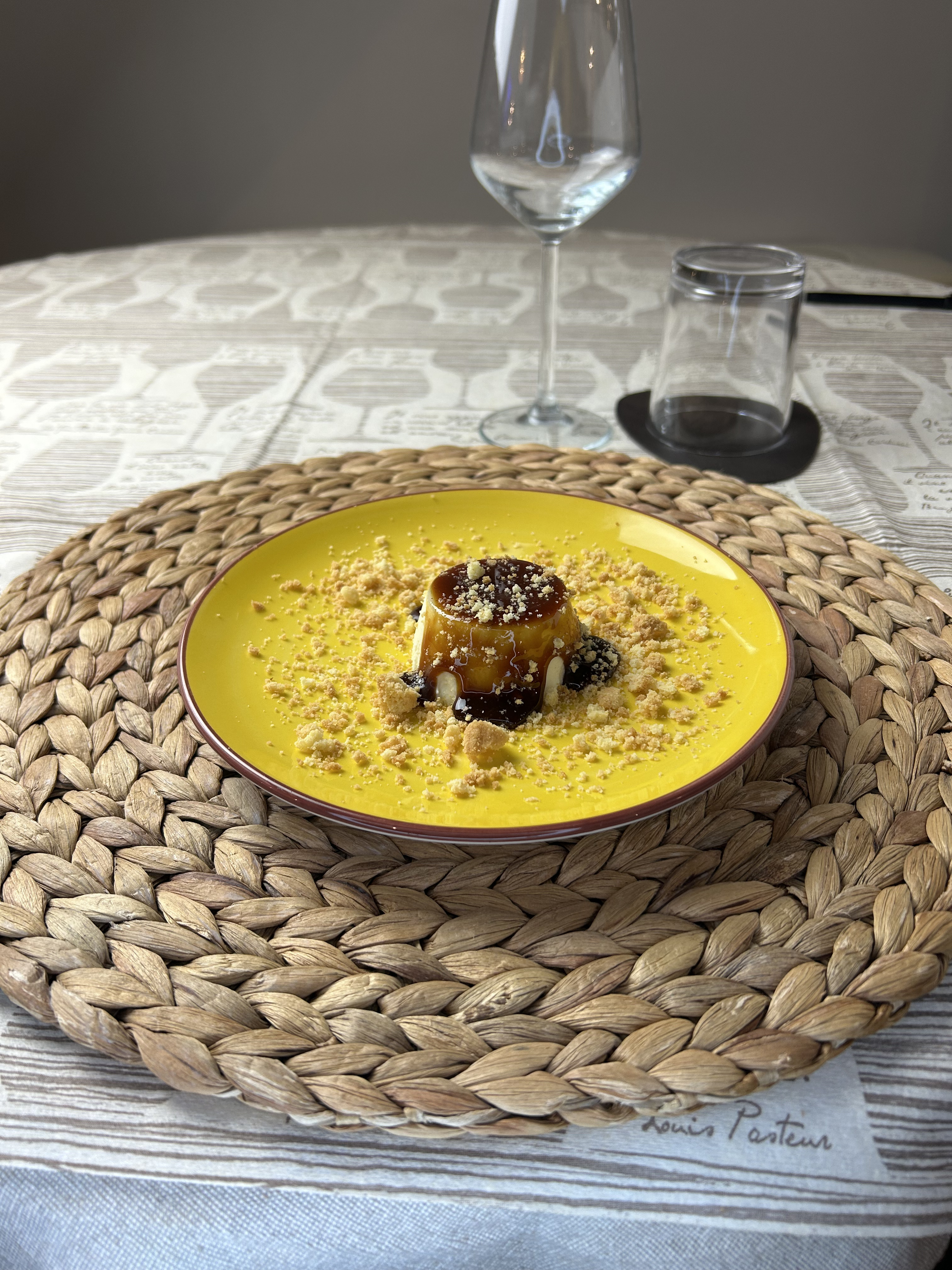 Crème caramel su un piatto giallo, con un calice a tavola
