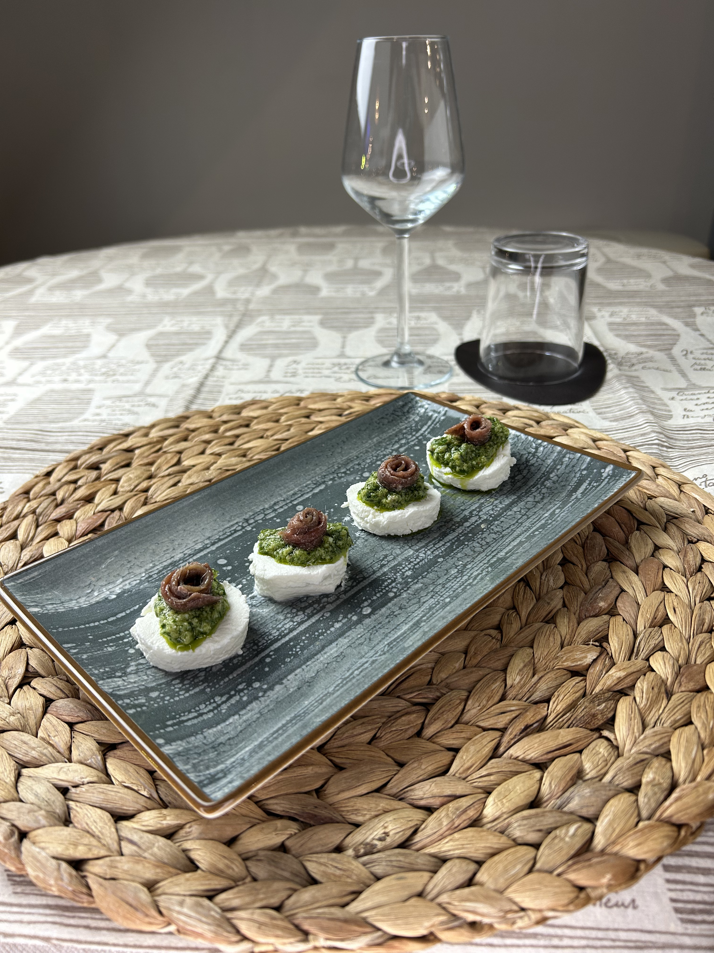 Tomini con bagnetto verde e acciuga, serviti su un piatto in ceramica