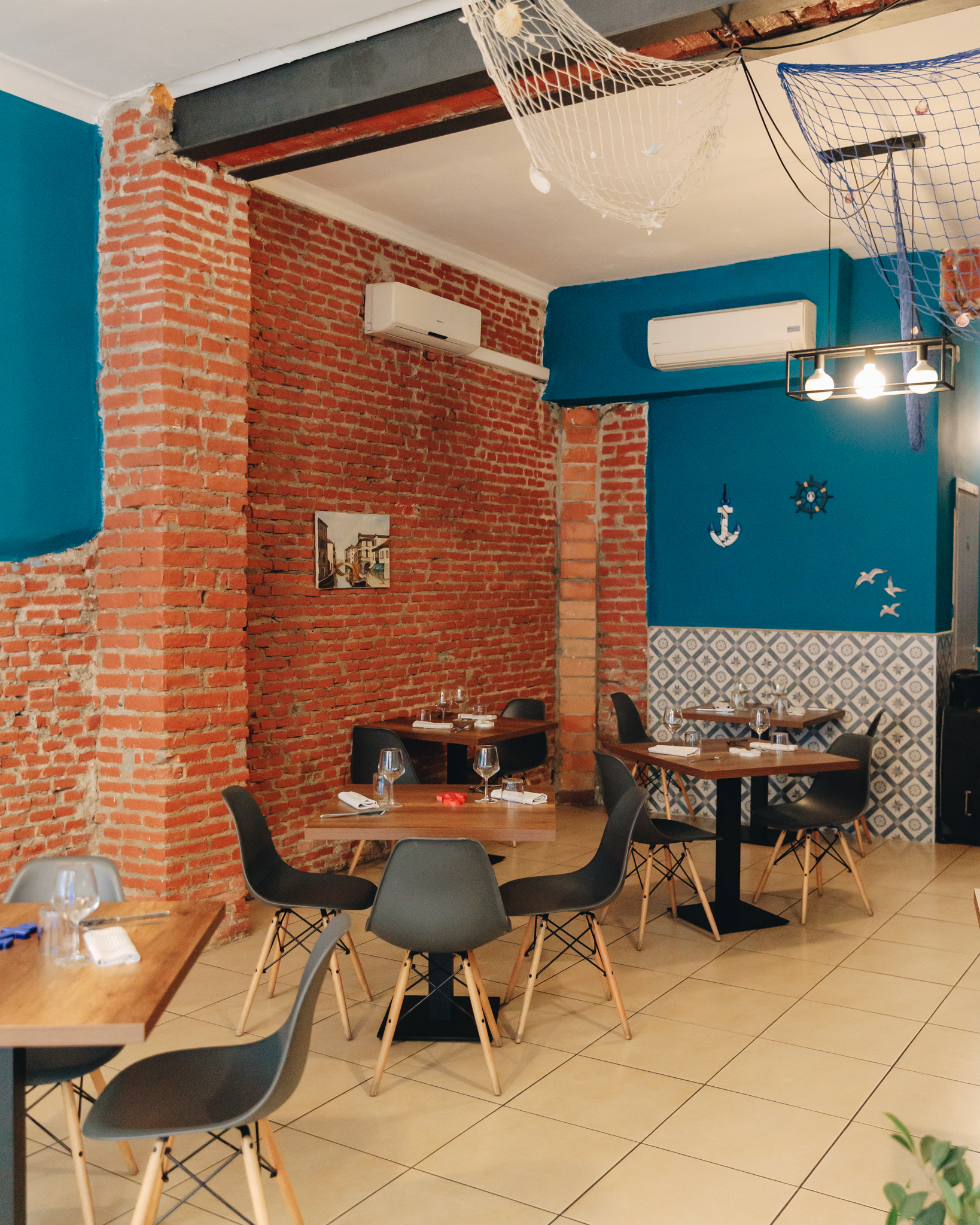 La sala del ristorante con pareti azzurre e mattoni a vista