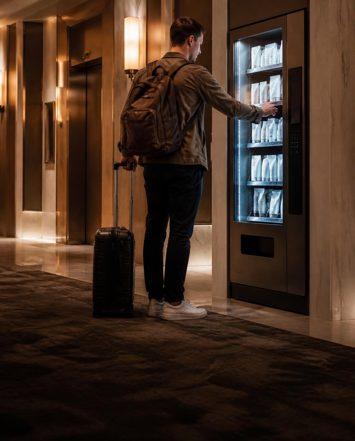 Hotel guest with a suitcase using a vending machine near the elevators