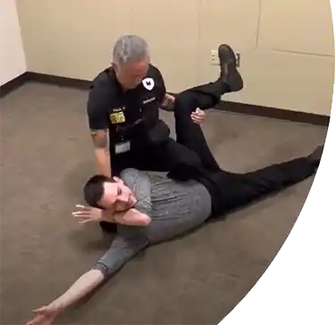 A self-defense instructor demonstrating a restraint technique in a workplace setting