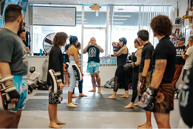 A diverse group participates in a kickboxing class at Stadium MMA in Port Orange, Florida with the class receiving instruction from the head coach on how to strike.