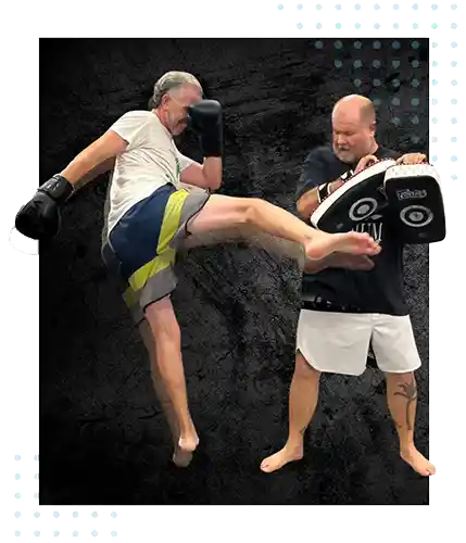 Two men training Muay Thai in a Port Orange, Florida gym. The guy on the let is throwing a strong kick and the guy on the right is holding the boxing pads.