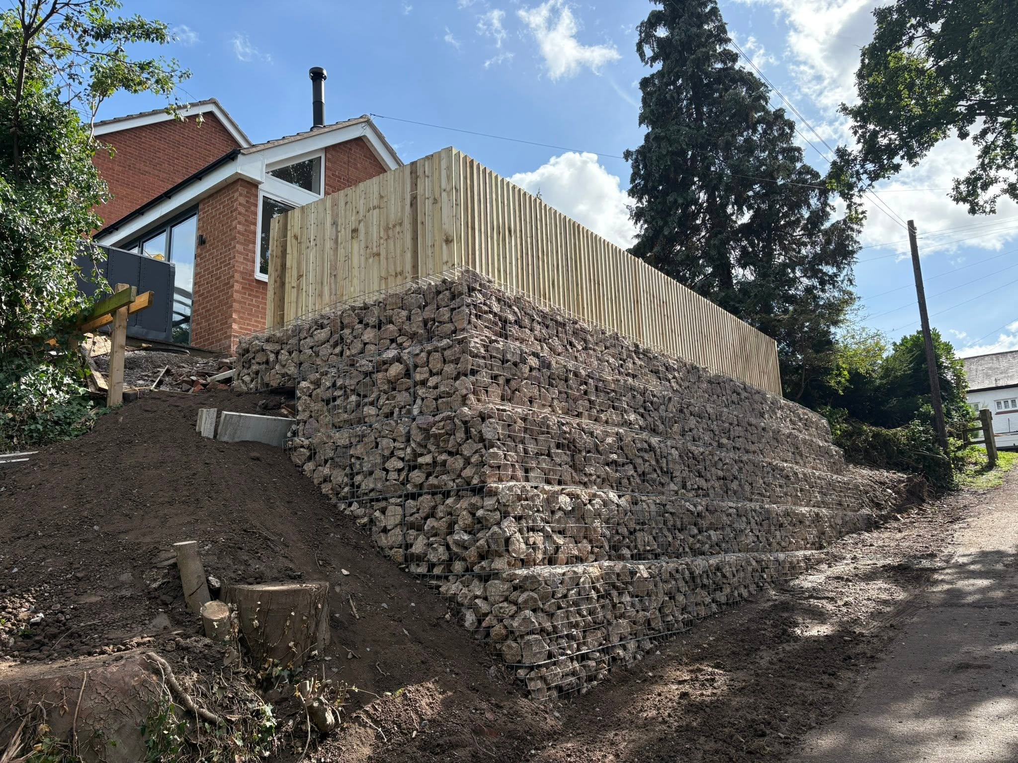Gabion retaining wall after: stepped stone filled wall and fencing