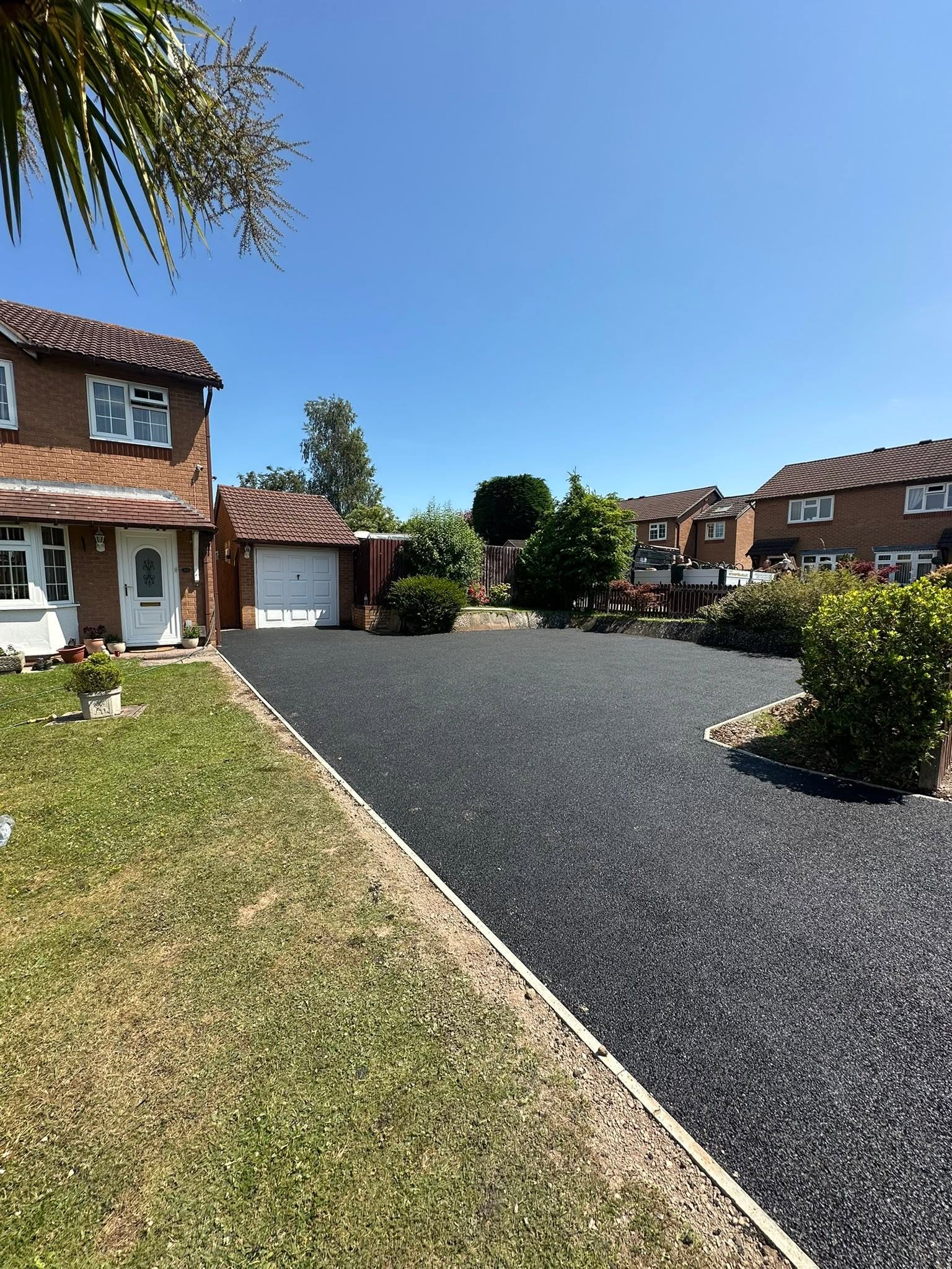 Tarmac driveway after: smooth black tarmac with concrete edging