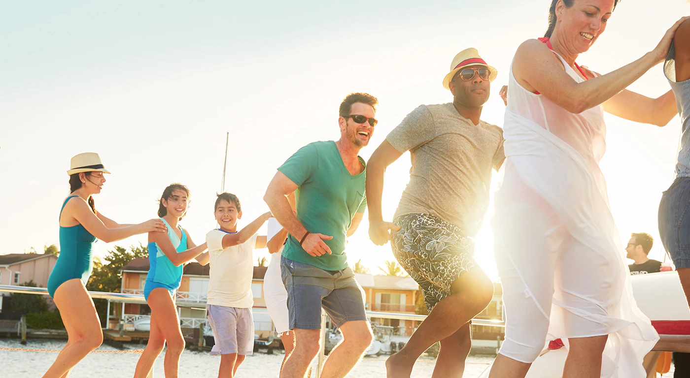 A group of cruise guests dancing in a line around the deck of the ship