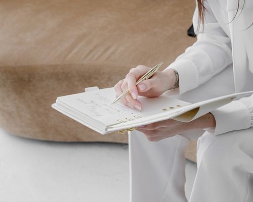 Woman writing strategic notes in a planner, representing clarity and direction in a 90-day Strategy Intensive.