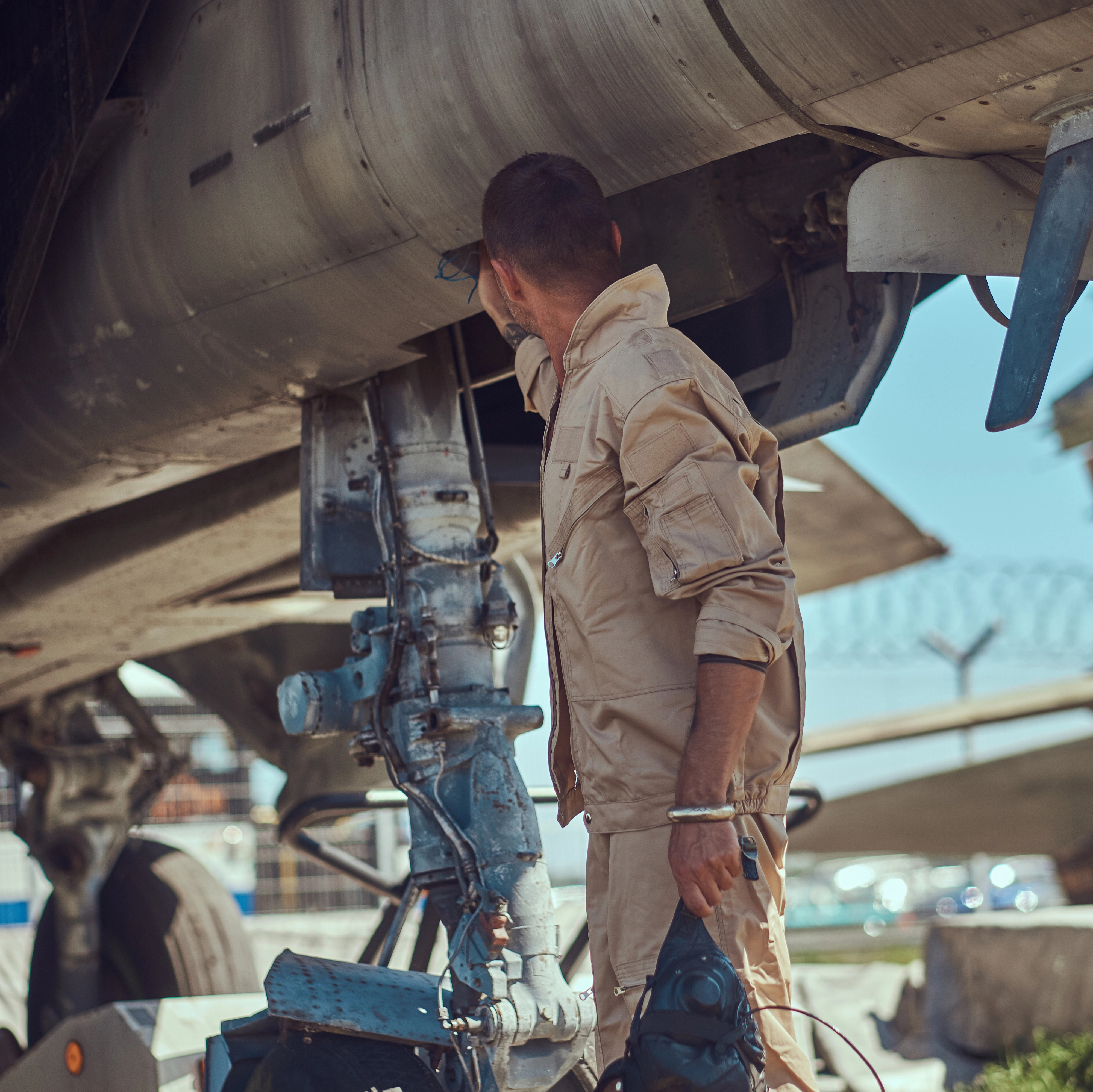 Aircraft technician performing maintenance inspection under airplane fuselage in hangar