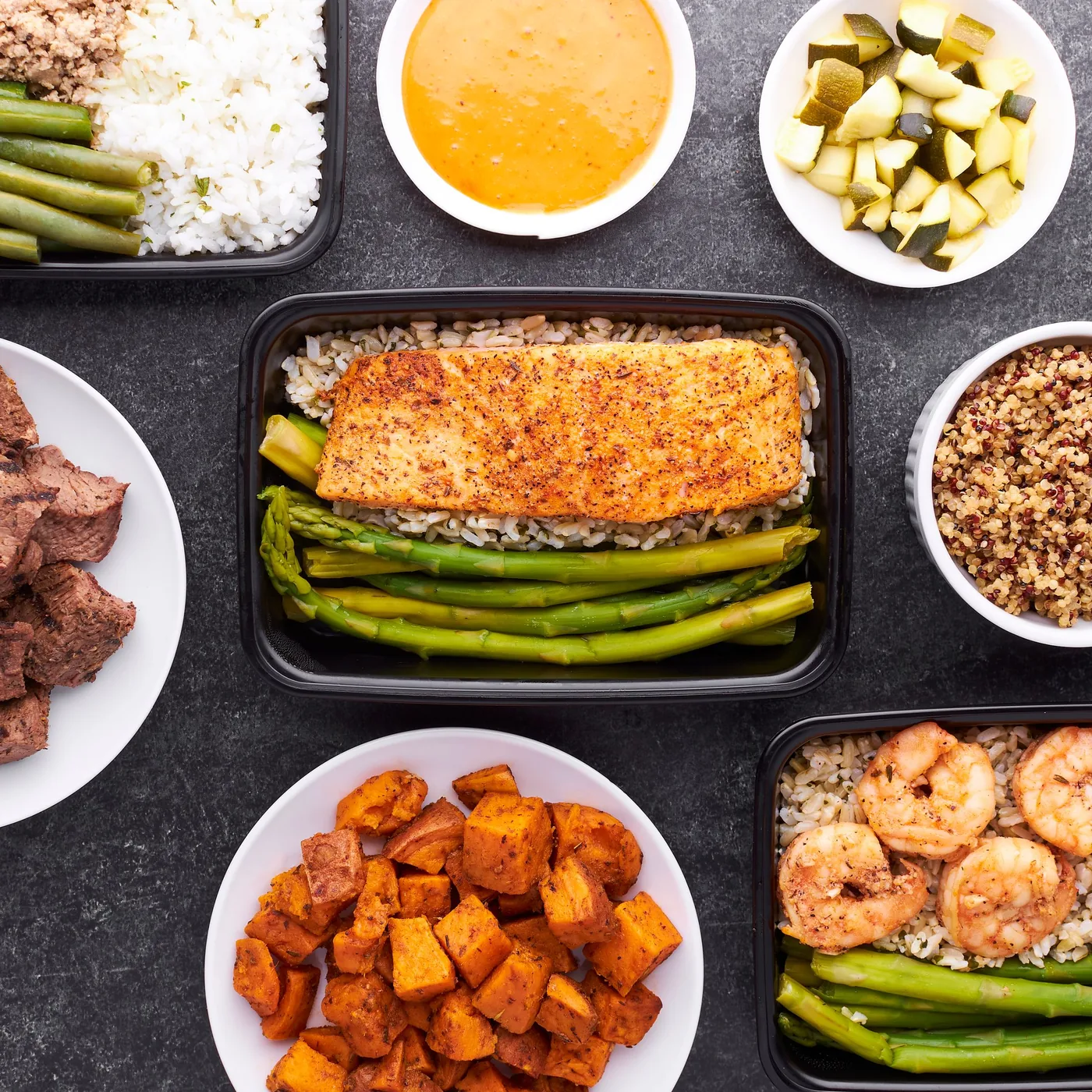 Plates of salmon, roasted vegetables, rice and greens laid out for the week