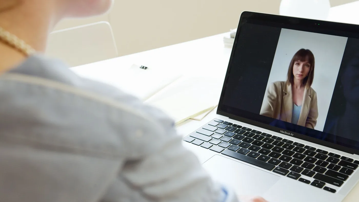 A woman on a video call with a coach on her laptop