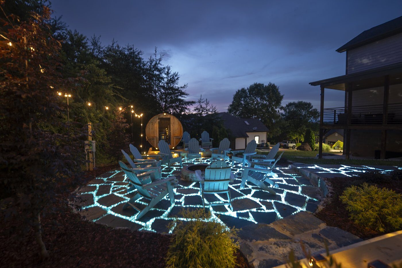 Glowing fire pit and outdoor patio at night at Ashe & Ember
