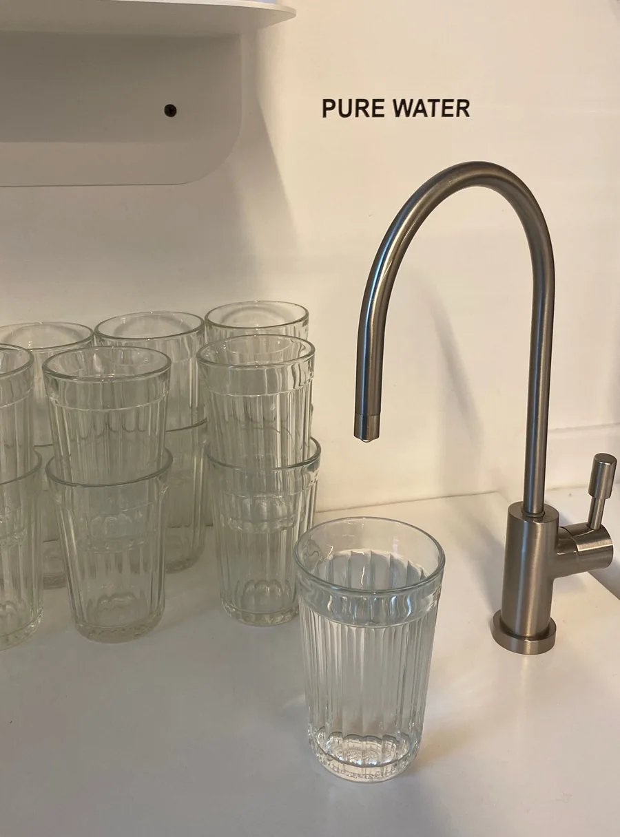 Dedicated drinking-water faucet below a Pure Water label, beside stacked clear glasses