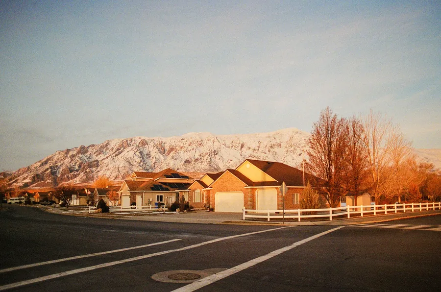 Suburban street and homes at sunrise below snow-covered Wasatch mountains