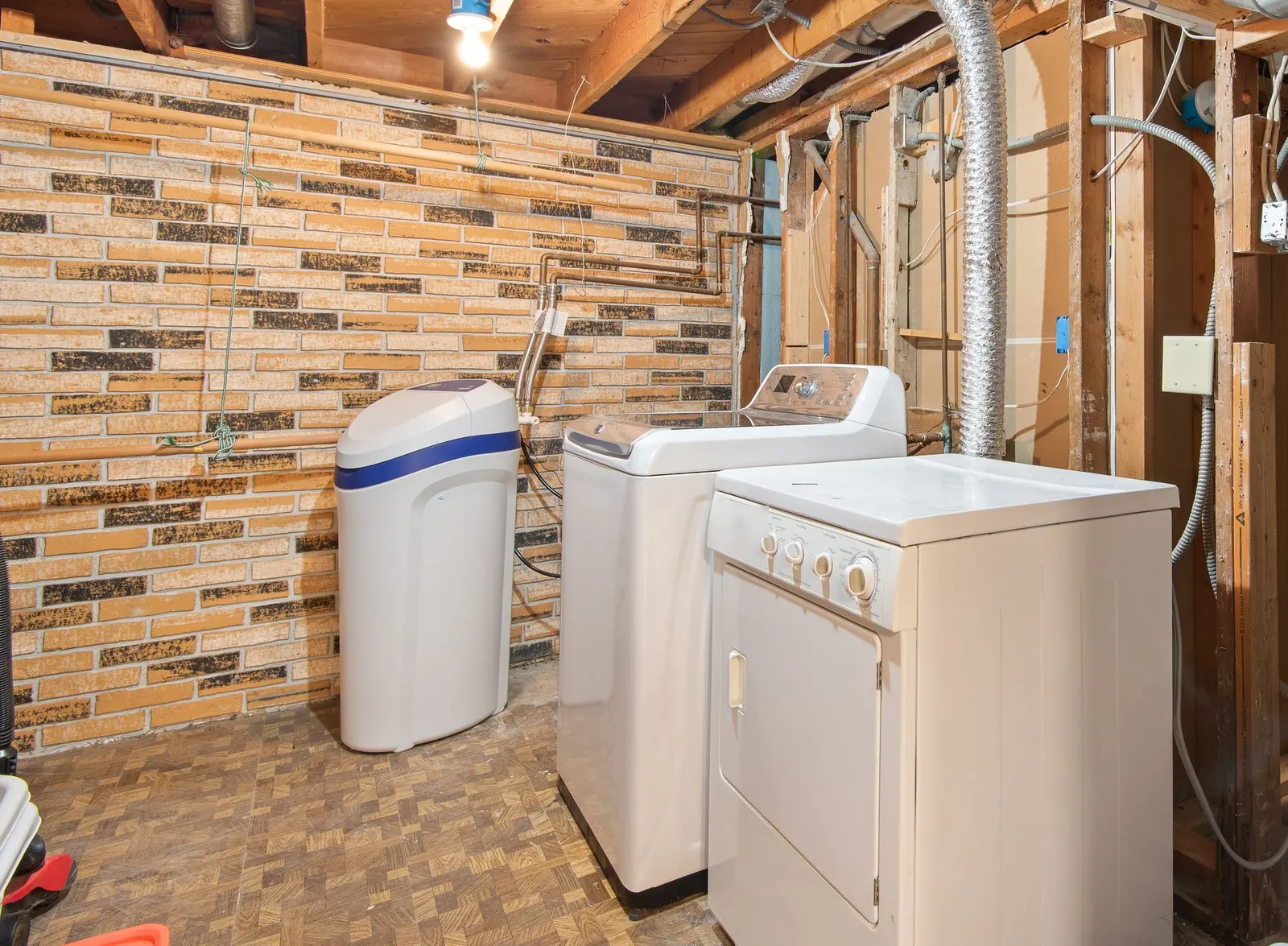 Cabinet-style water softener next to a washing machine in a basement laundry room