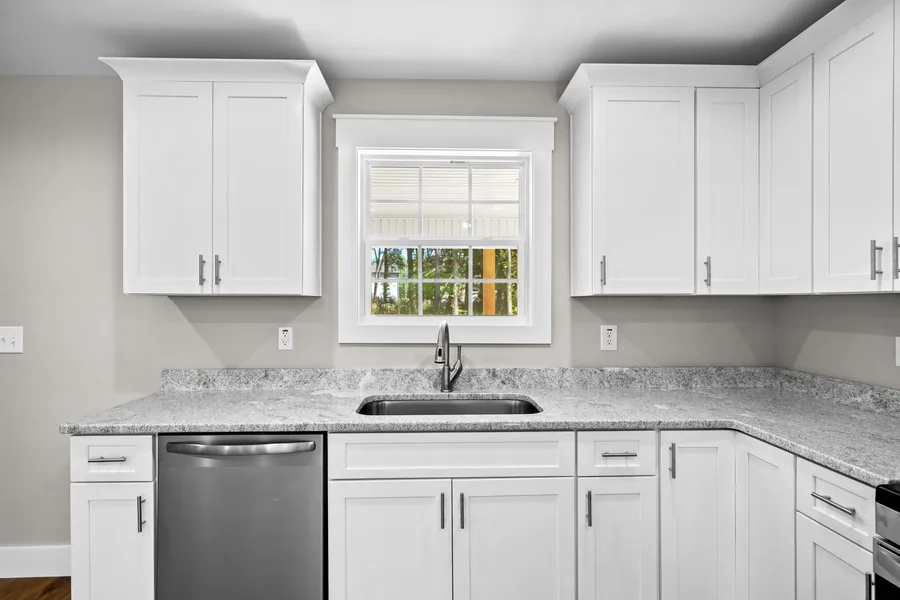 Bright kitchen with white cabinets and a sink beneath a window
