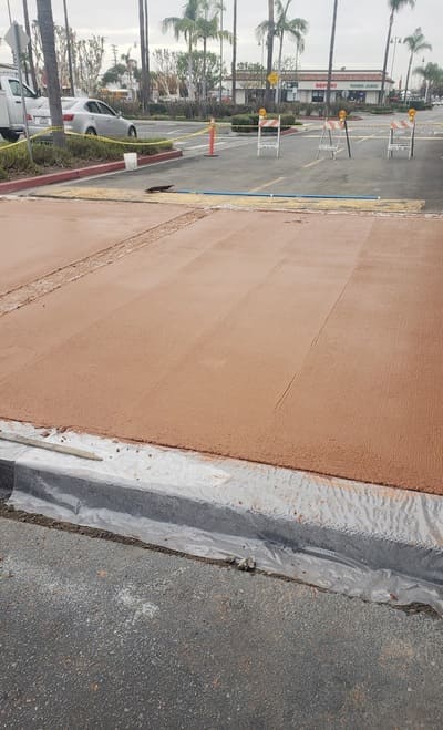 A newly poured concrete sidewalk in a commercial area