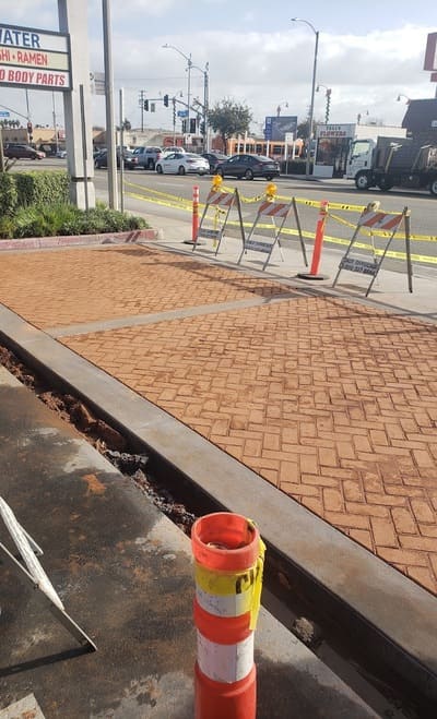 A stamped concrete sidewalk featuring a decorative herringbone pattern