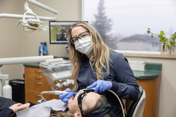 A hygienist at Orchard Heights Dental attentively explaining care to a relaxed older patient