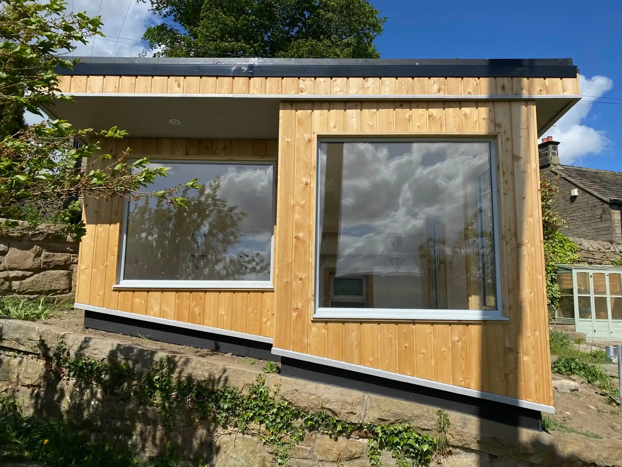 Garden room sitting level on foundations in a gently sloping garden
