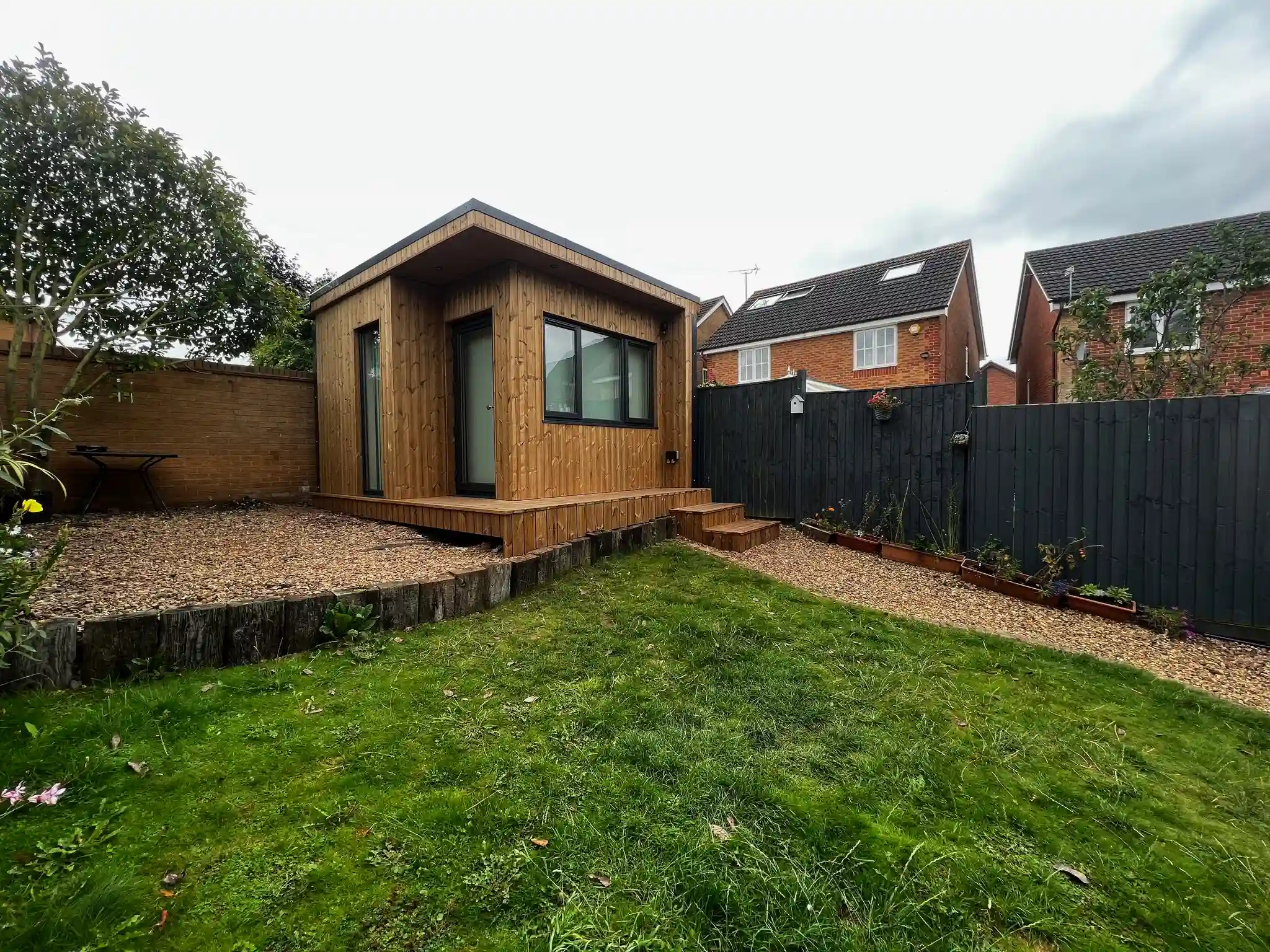 Finished garden room on solid foundations glowing warmly in a UK garden