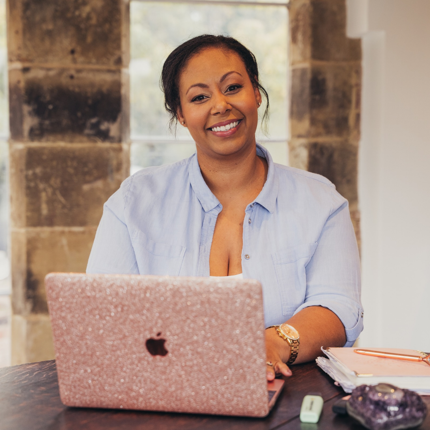 Em smiling at her desk with her laptop