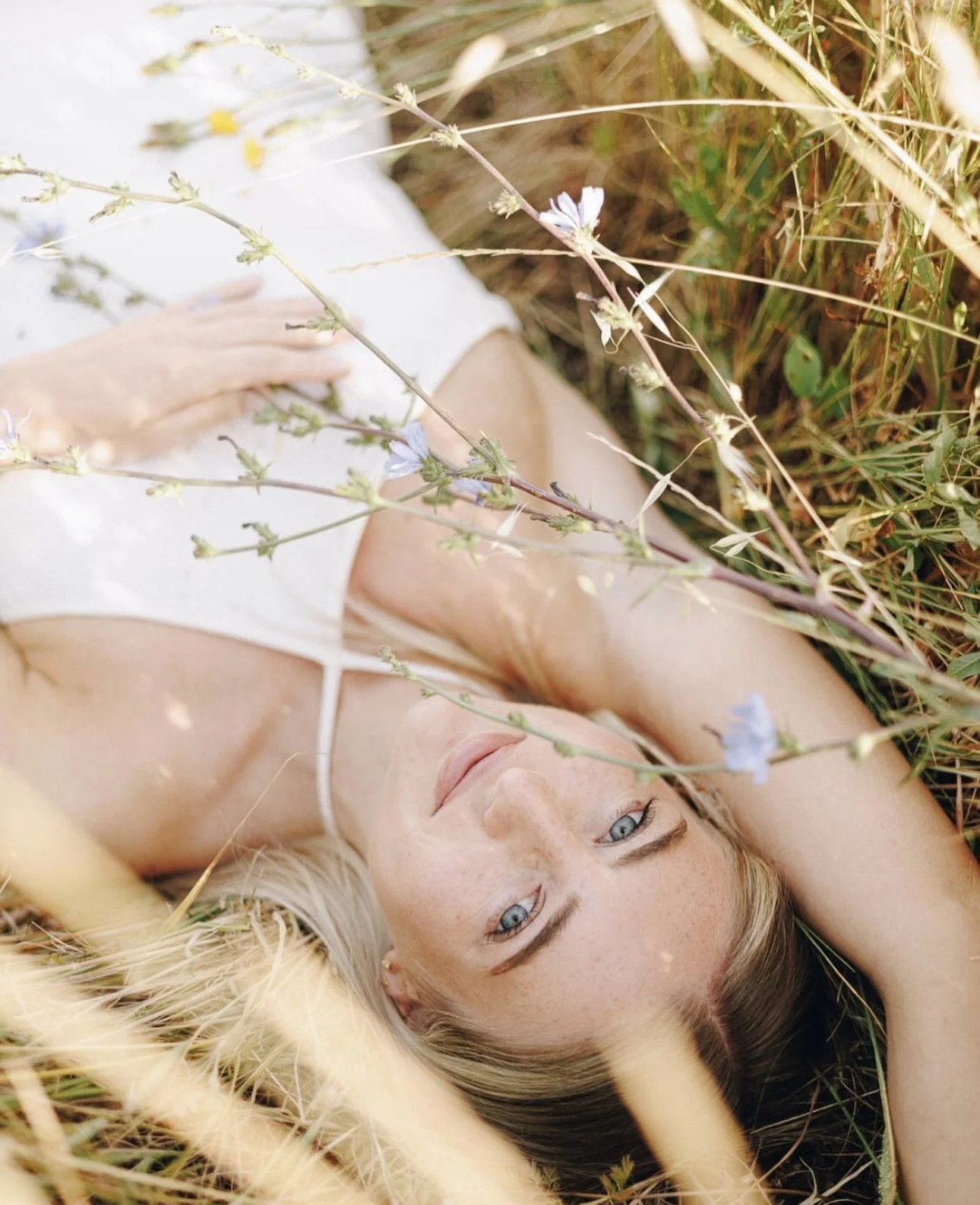 Caitlin lying in long grass and wildflowers, looking up