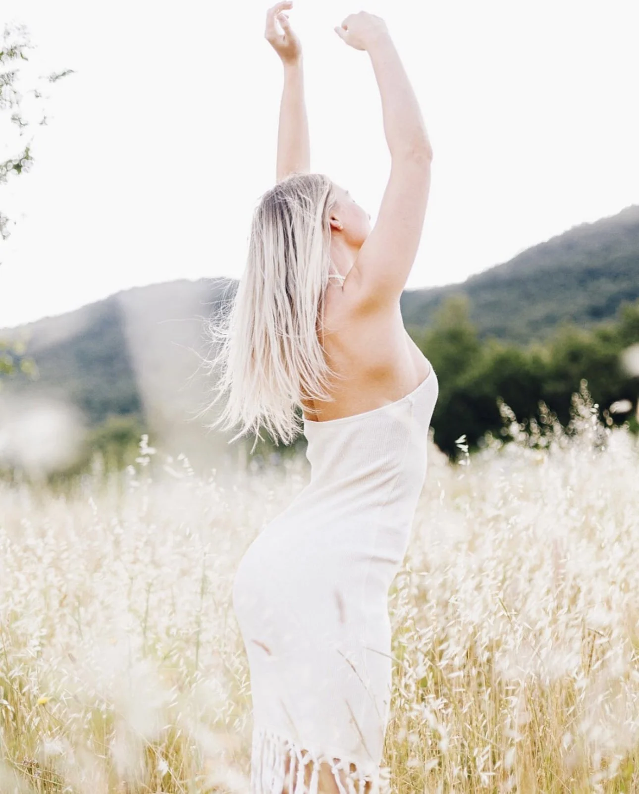 Caitlin with arms raised in a field of tall grass