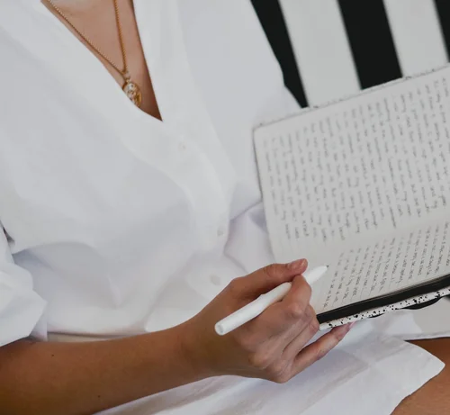 Hands holding a pen over a handwritten journal