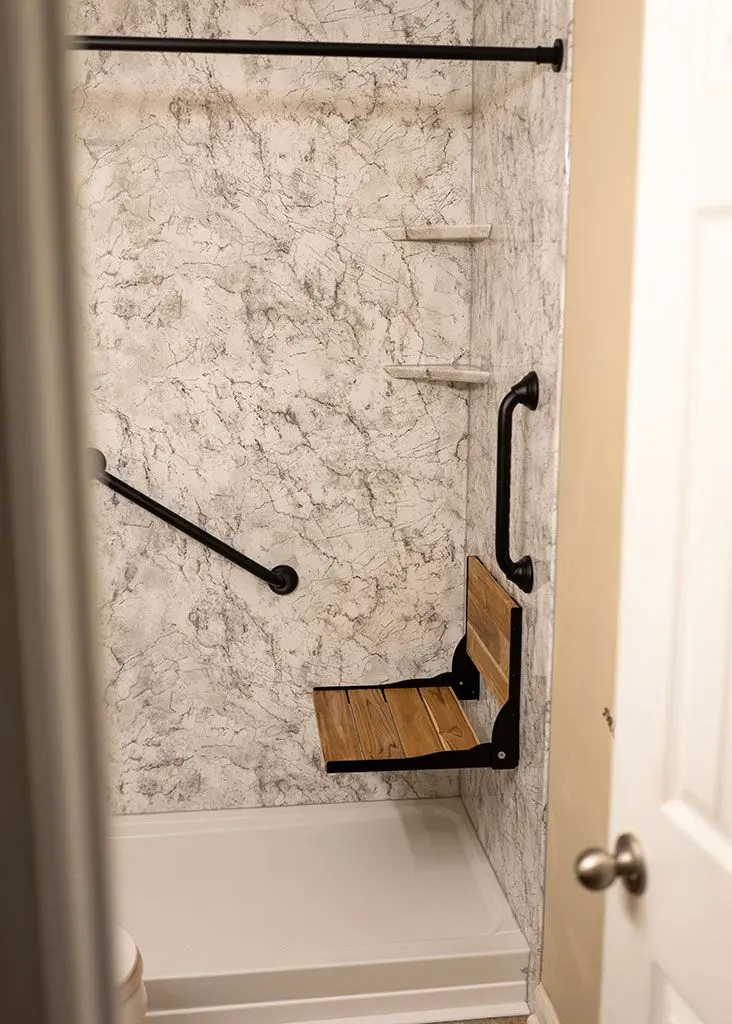 Converted shower with grab bars and a fold-down seat